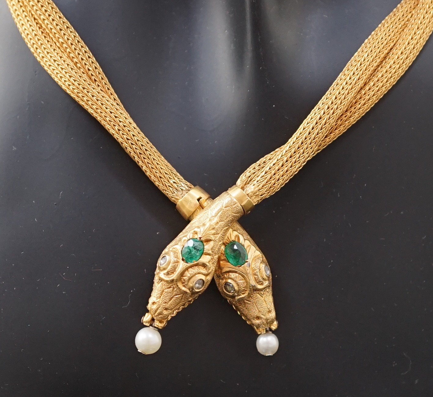 An early 20th century multi-strand gold, emerald, rose cut diamond and cultured pearl drop set twin headed serpent necklace